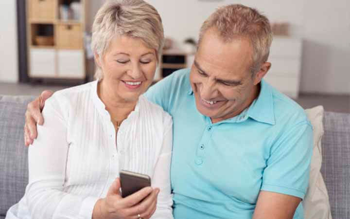 casal feliz com o celular na mão vendo sobre empréstimo consignado