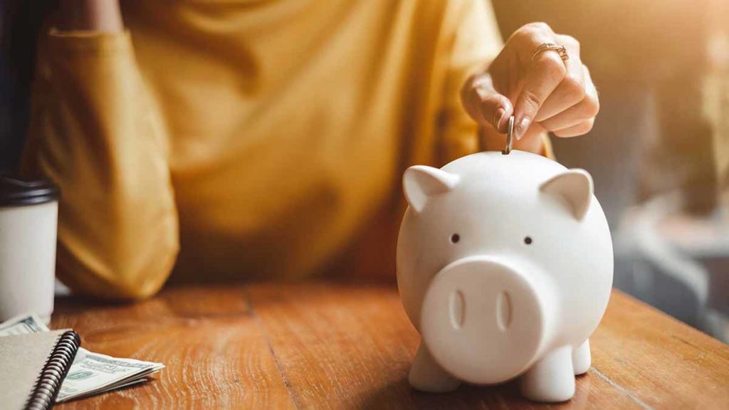 mulher guardando dinheiro num porco mostrando como juntar dinheiro ganhando pouco