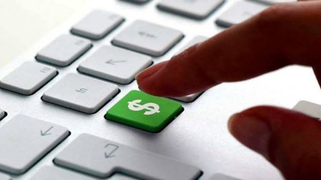 Precisando de Grana saiba como ganhar dinheiro na internet, teclado de um computador com um botao verde com um simbolo de cifrão quase apertado por um dedo.