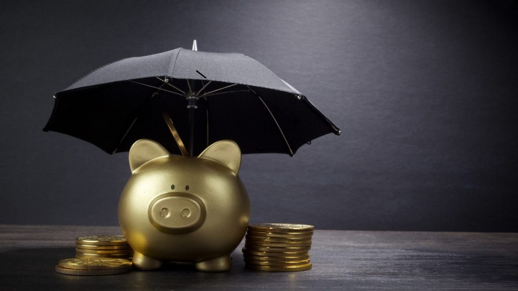 Empréstimo pessoal online X Empréstimo com agiota, Cofrinho de porco dourado com guarda chuvas e moedas ao seu redor